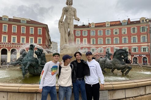 Friends stand in front of a fountain in Italy.